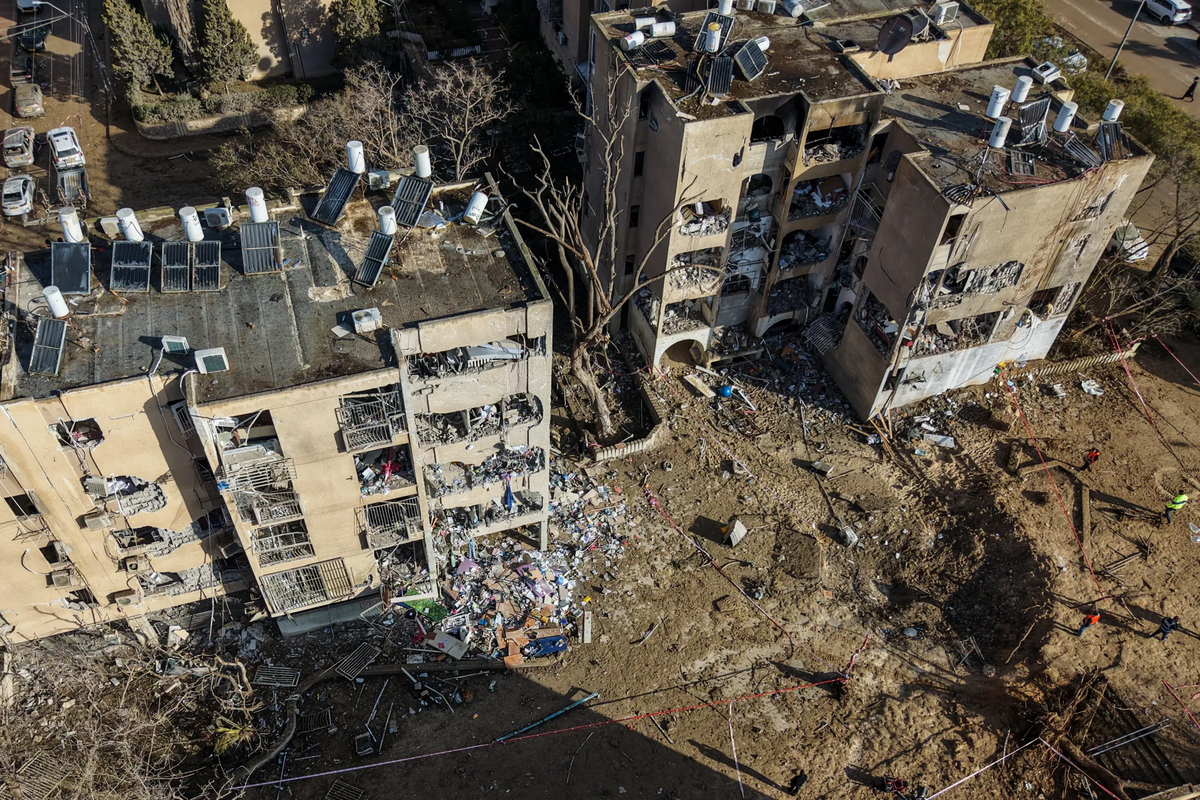 Aerial view of crater and damaged residential buildings in Arad after missile strikes.