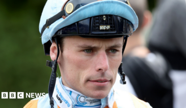 A close-up of a jockey wearing a helmet with a serious facial expression