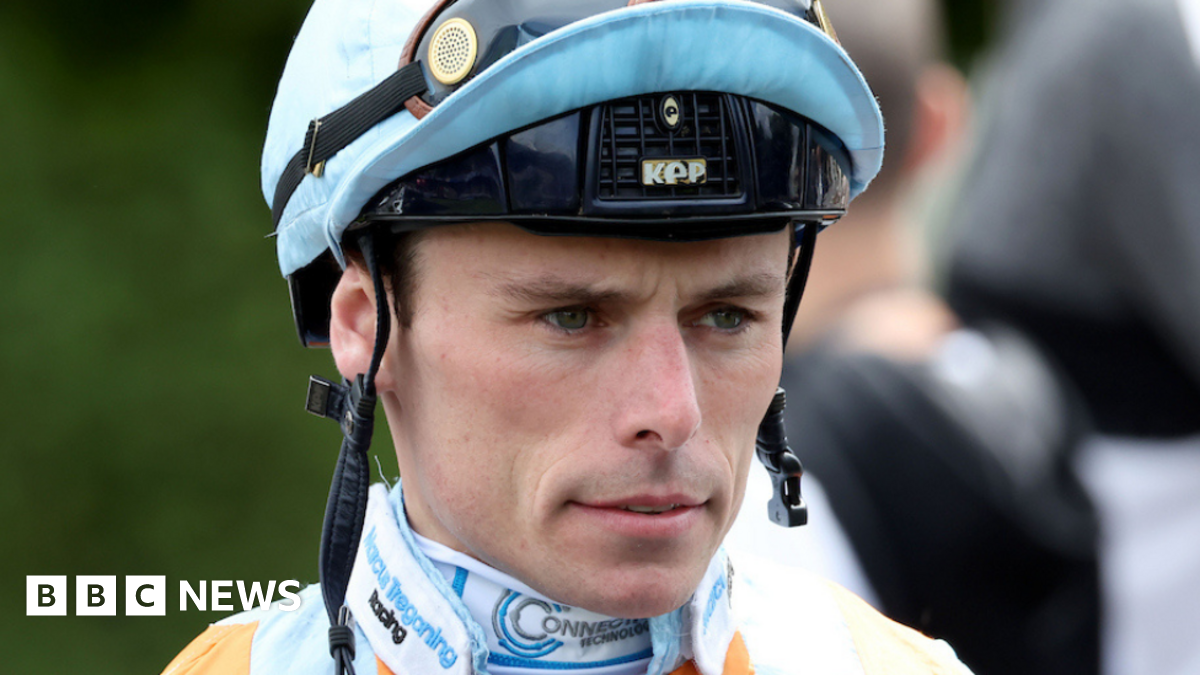 A close-up of a jockey wearing a helmet with a serious facial expression