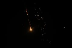 A missle flies through the air, lit up against the night sky