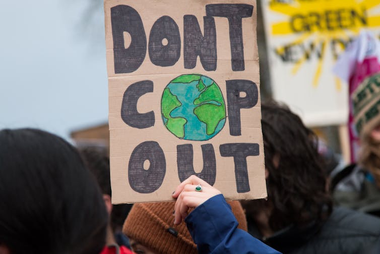 person holds 'don't cop out' placard