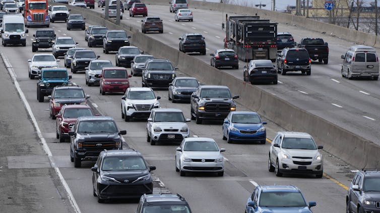 cars can be seen driving forward in several lanes on a major highway