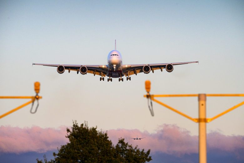 airbus a380 coming in to land at heathrow airport in london over trees and landing lights.