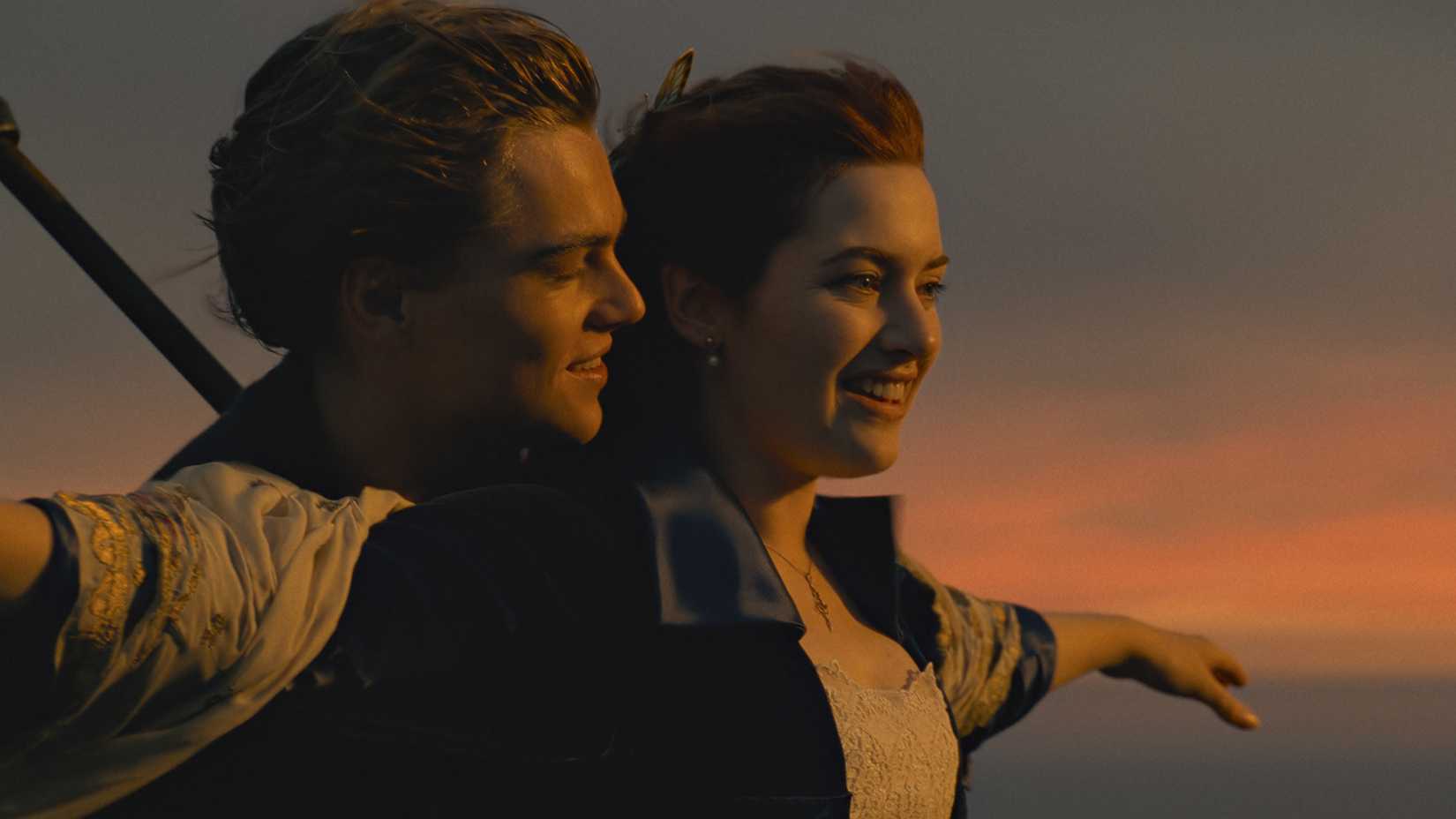 Jack hugs Rose from behind as they stand on the bow of the ship in Titanic