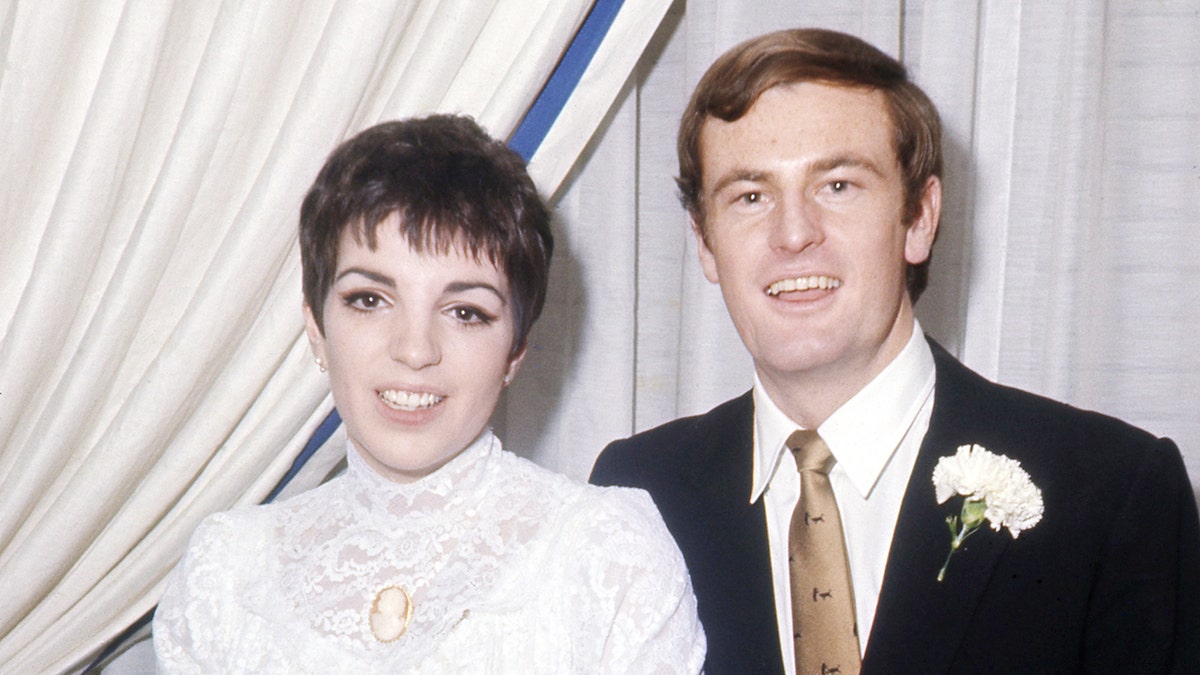 A close-up of Liza Minnelli in her wedding dress standing next to Peter Allen in a suit with a gold tie