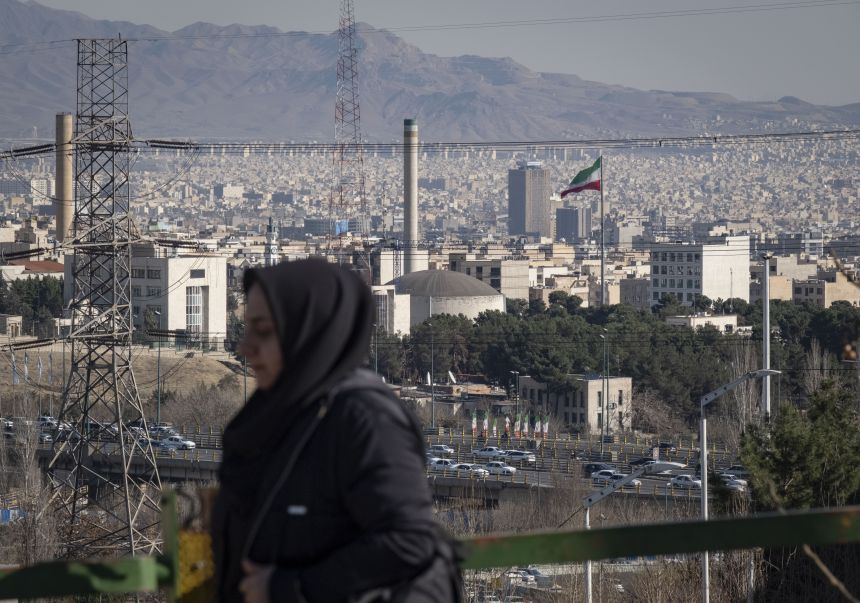 An Iranian woman walks past a view of Tehran's research reactor in Tehran, Iran, on February 26, 2026, the final day of Iran-US talks that are currently held in the city of Geneva.