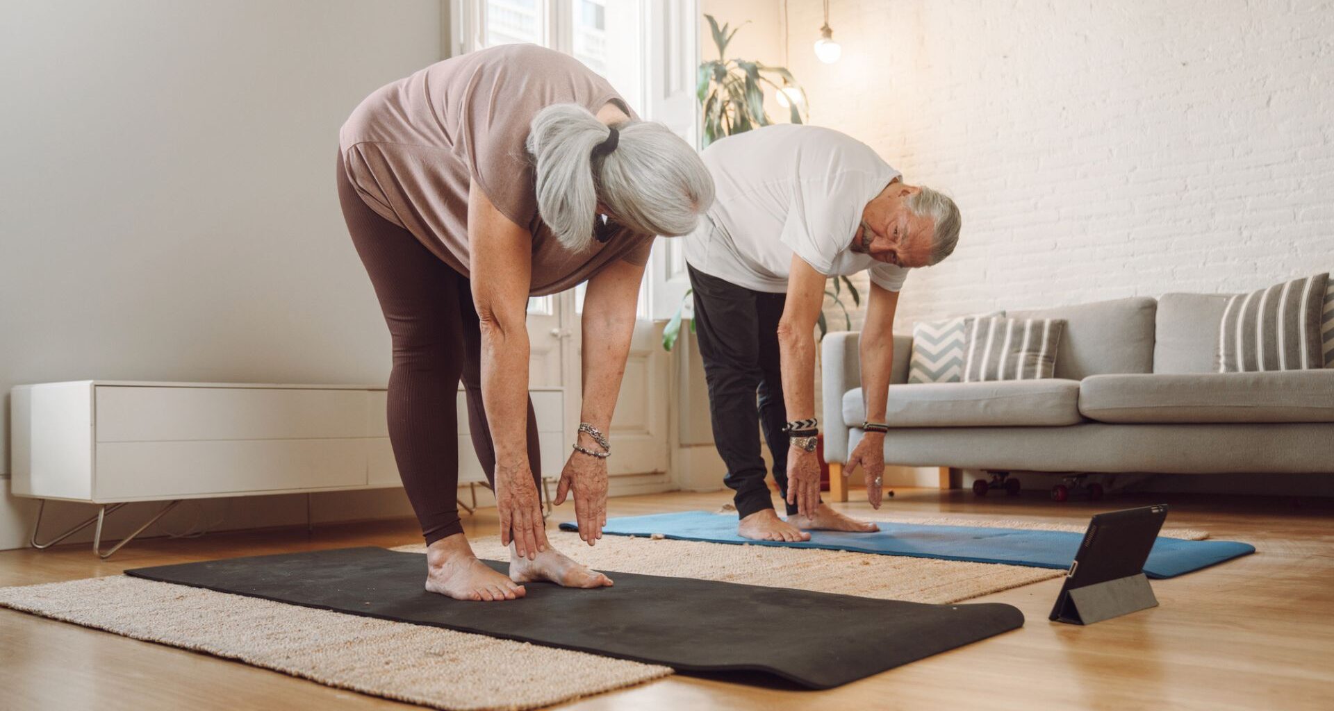 senior couple touch toes on yoga mats
