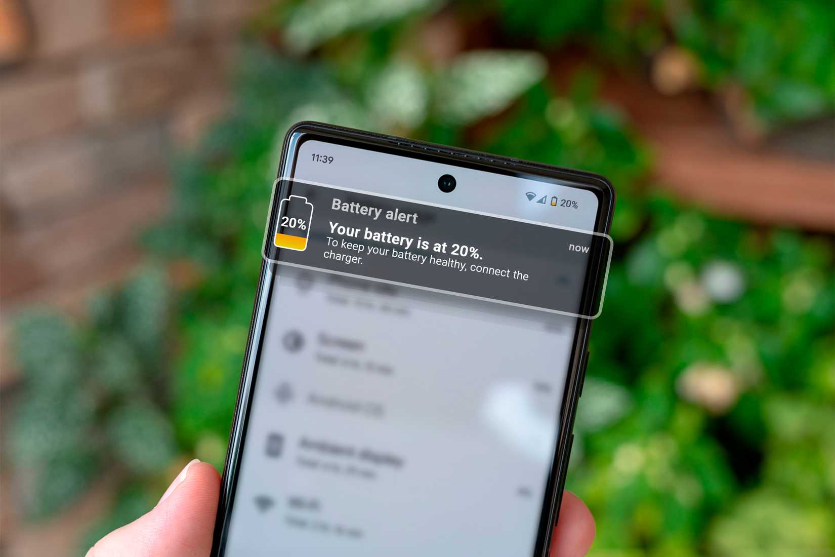 Hand holding a smartphone with a battery charge notification.