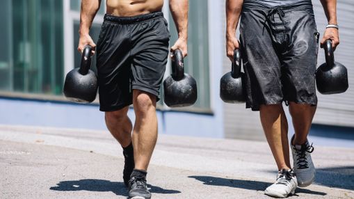 Two muscular men performing farmer's carry