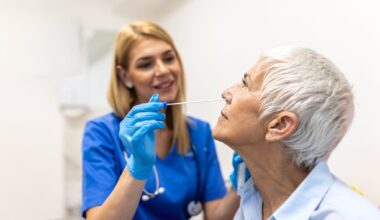 Nurse Taking Nasal Swab Test from Senior Woman in Clinic. Healthcare And Medicine concept. Professional doctor in blue gloves performing covid-19 or flu diagnostic procedure for elderly patient.