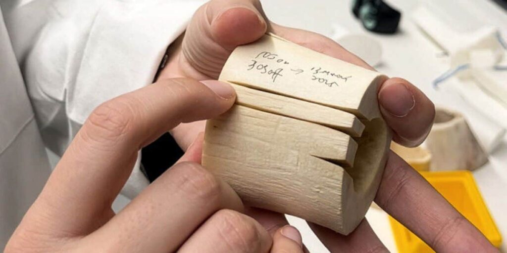 A wooden object being held by a person's hand in a laboratory setting.