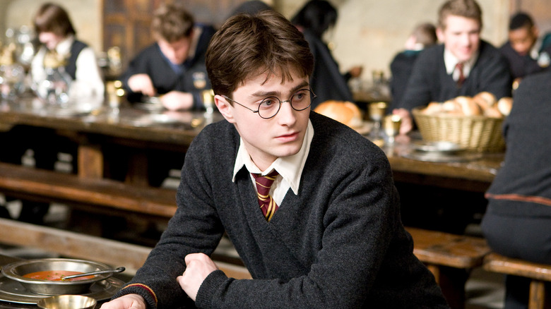 Harry sitting at a table in the Great Hall looking to the side in Harry Potter and the Prisoner of Azkaban