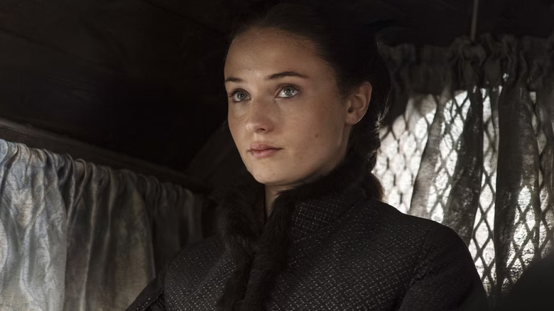 Sophie Turner as Sansa wearing all black in a carriage in Game of Thrones