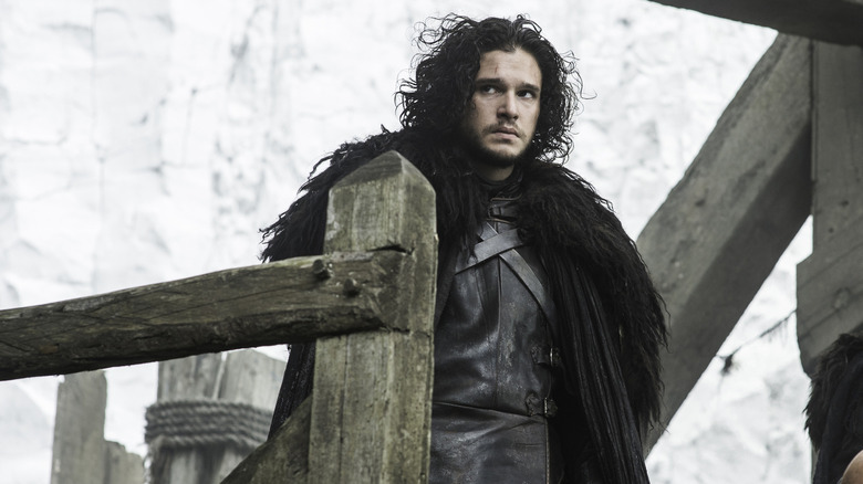 Kit Harington as Jon Snow standing on a platform in front of a wall of ice in Game of Thrones