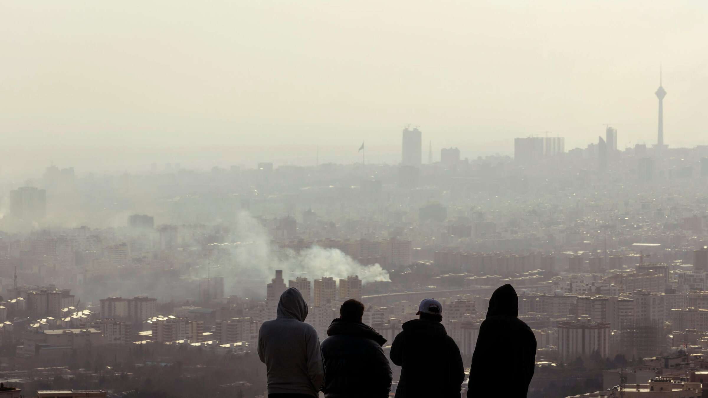 Men watch from a hillside as a plume of smoke rises after an explosion in Tehran, Iran on March 2.