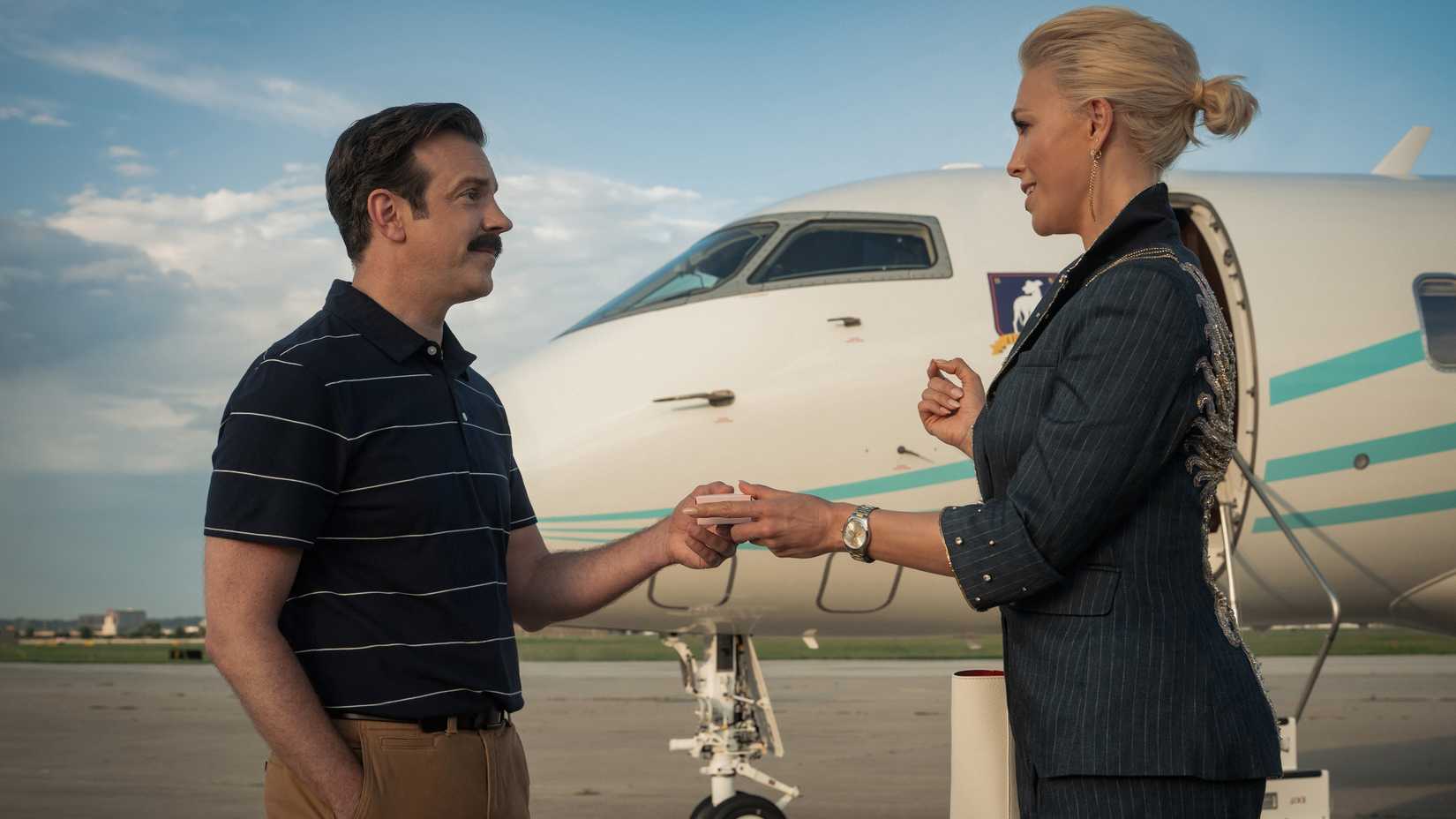 Jason Sudeikis' Ted handing Hannah Waddingham's Rebecca a box of biscuits next to a private jet in Ted Lasso season 4