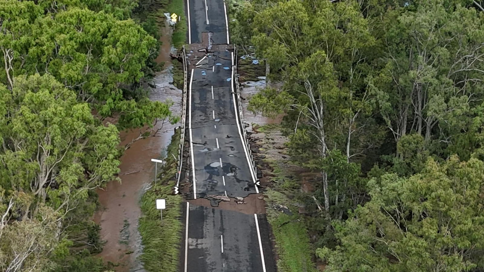 An aerial shot of a damaged bridge on a highway