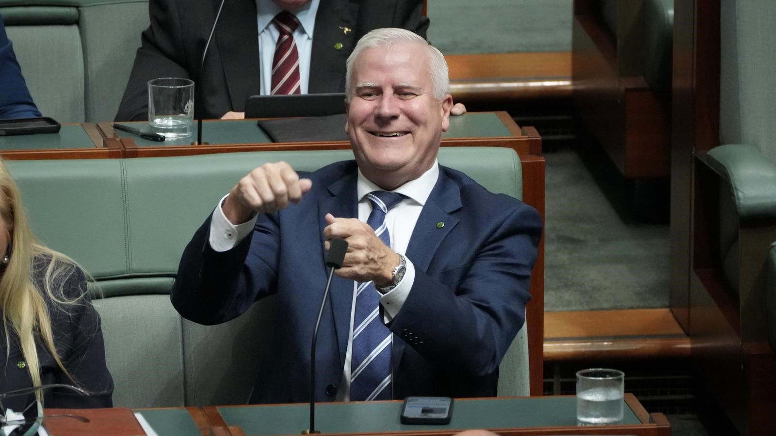 Michael McCormack smiles as he mimes reeling in a fishing line.