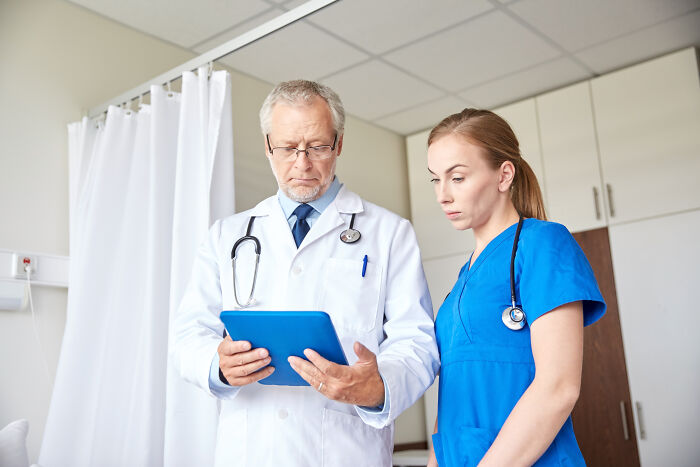 Doctor and nurse reviewing patient information on tablet, revealing behind-the-scenes events doctors wouldn’t want patients to know.