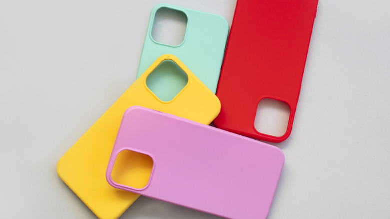 A teal, light purple, red, and yellow cellphone cases piled next to each other against a gray background