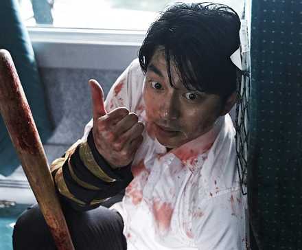 Gong Yoo hiding behind a chair holding a bat in Train to Busan