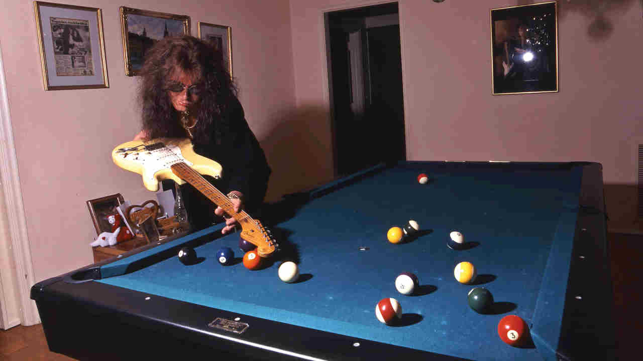 Yngwie Malmsteen playing pool with a guitar