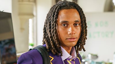 A student (Toby, Boarders) poses with a purple school uniform.