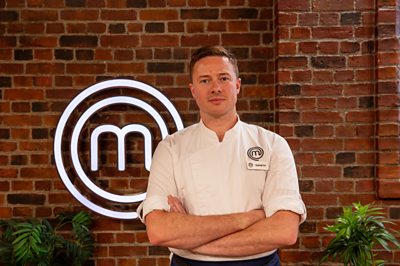 A man stands in the MasterChef studio with a GARETH name badge