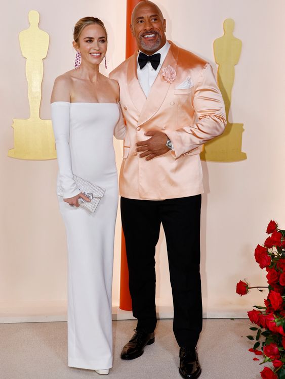 Dwayne Johnson showing his softer side in peach satin with Emily Blunt at the 2023 Oscars. Pic: Reuters
