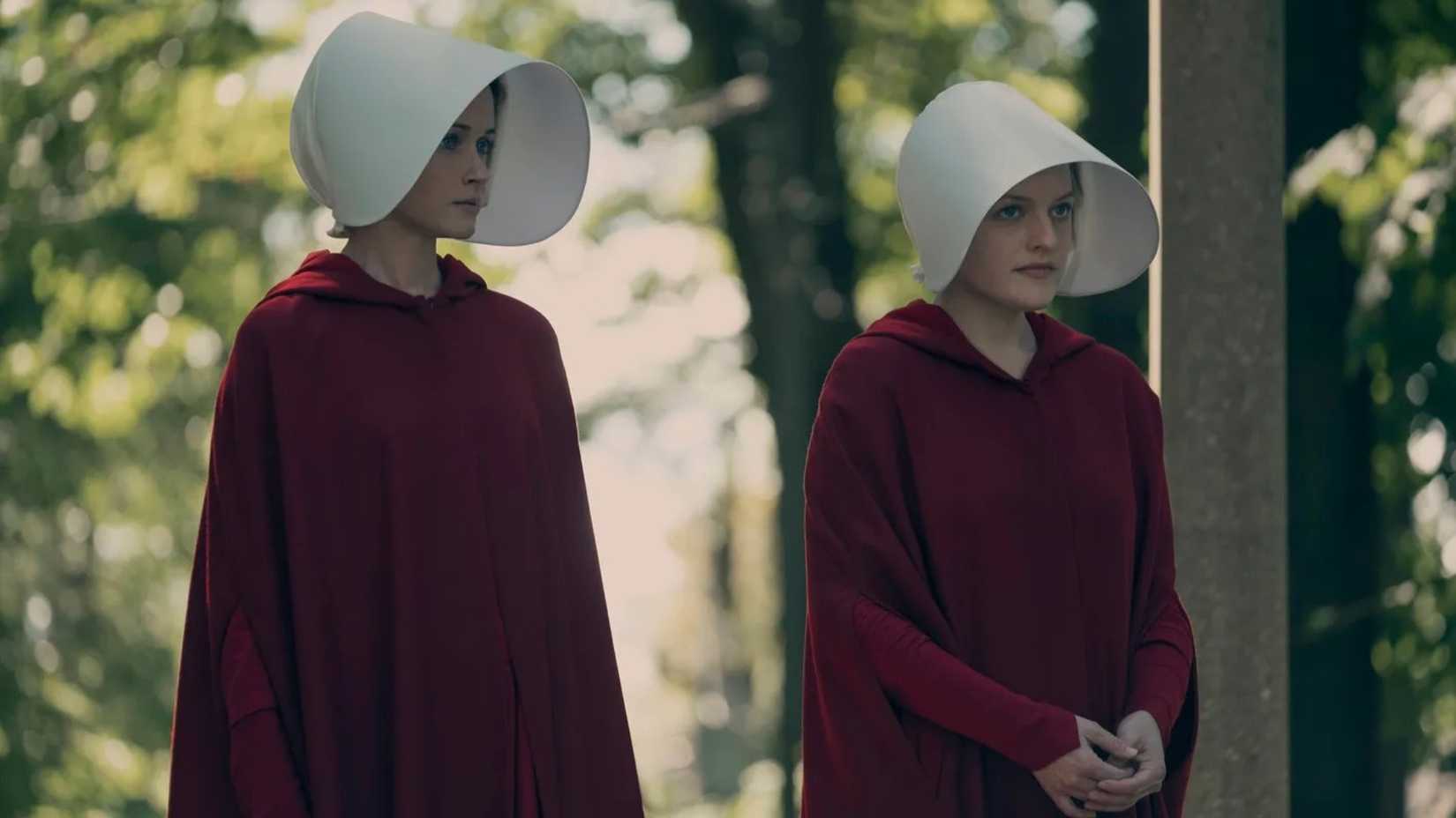 Two women in red robes and white head covers in Margaret Atwood's The Handmaid's Tale.