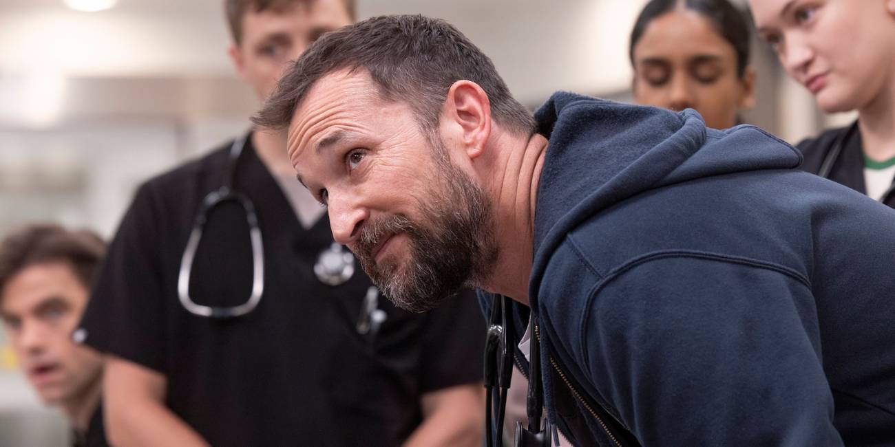 Noah Wyle as Dr. Robby looking up in a group of doctors in The Pitt.