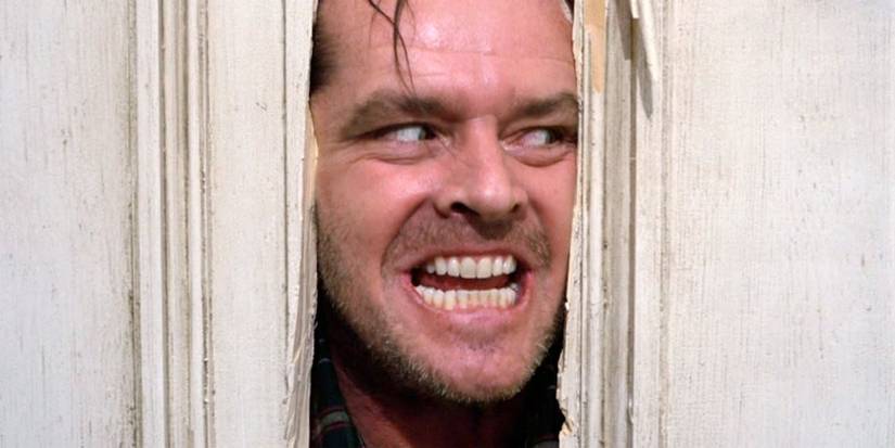 Jack Nicholson smiling while peeking through a door in The Shining