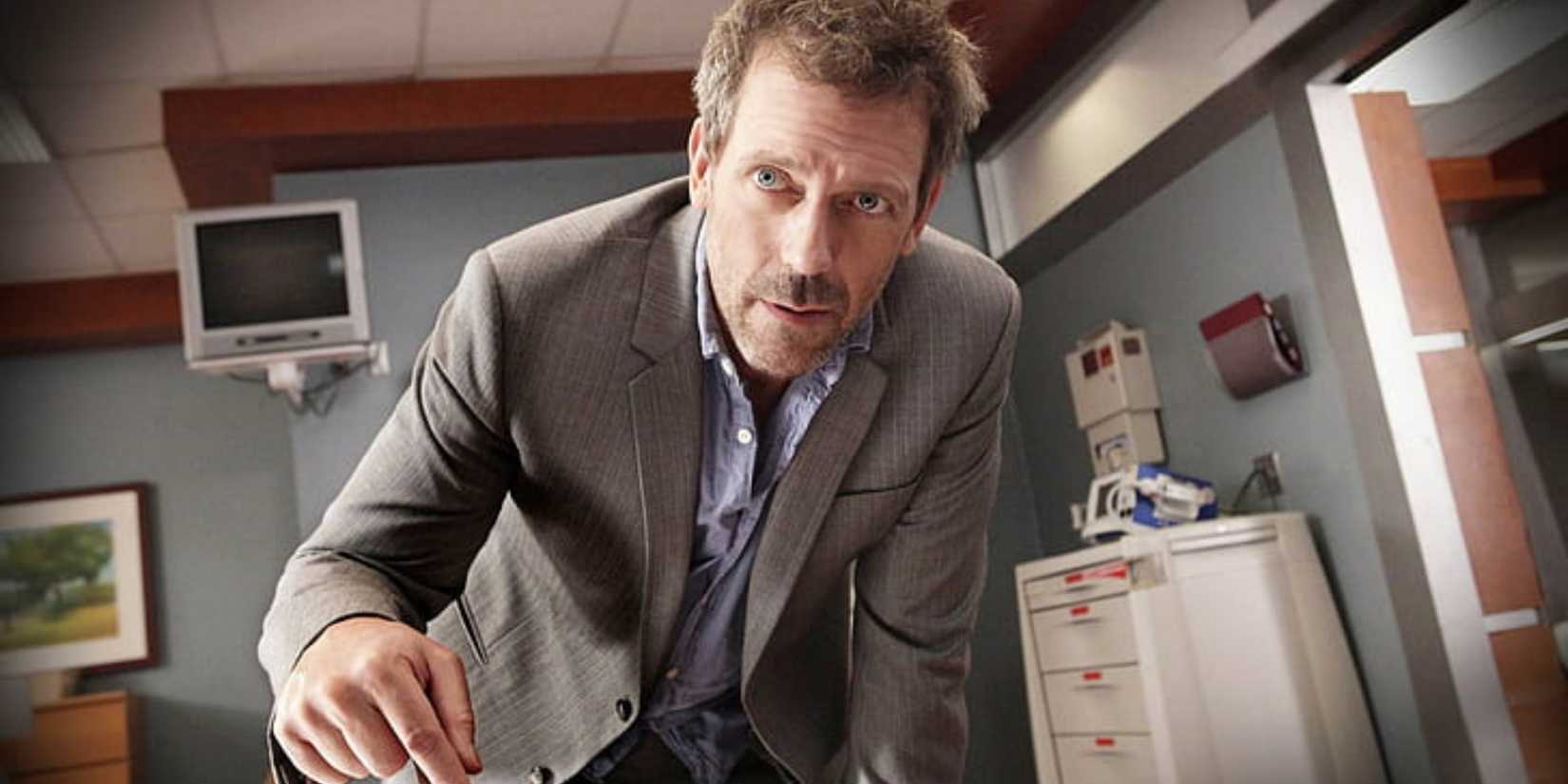 Hugh Laurie as Dr. Gregory House standing in a hospital room, leaning over and looking at something, in House.