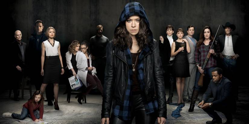 Tatiana Maslany wearing a hoodie and standing in front of the main Orphan Black characters
