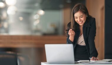 Professional appears happy while reading something on the laptop.