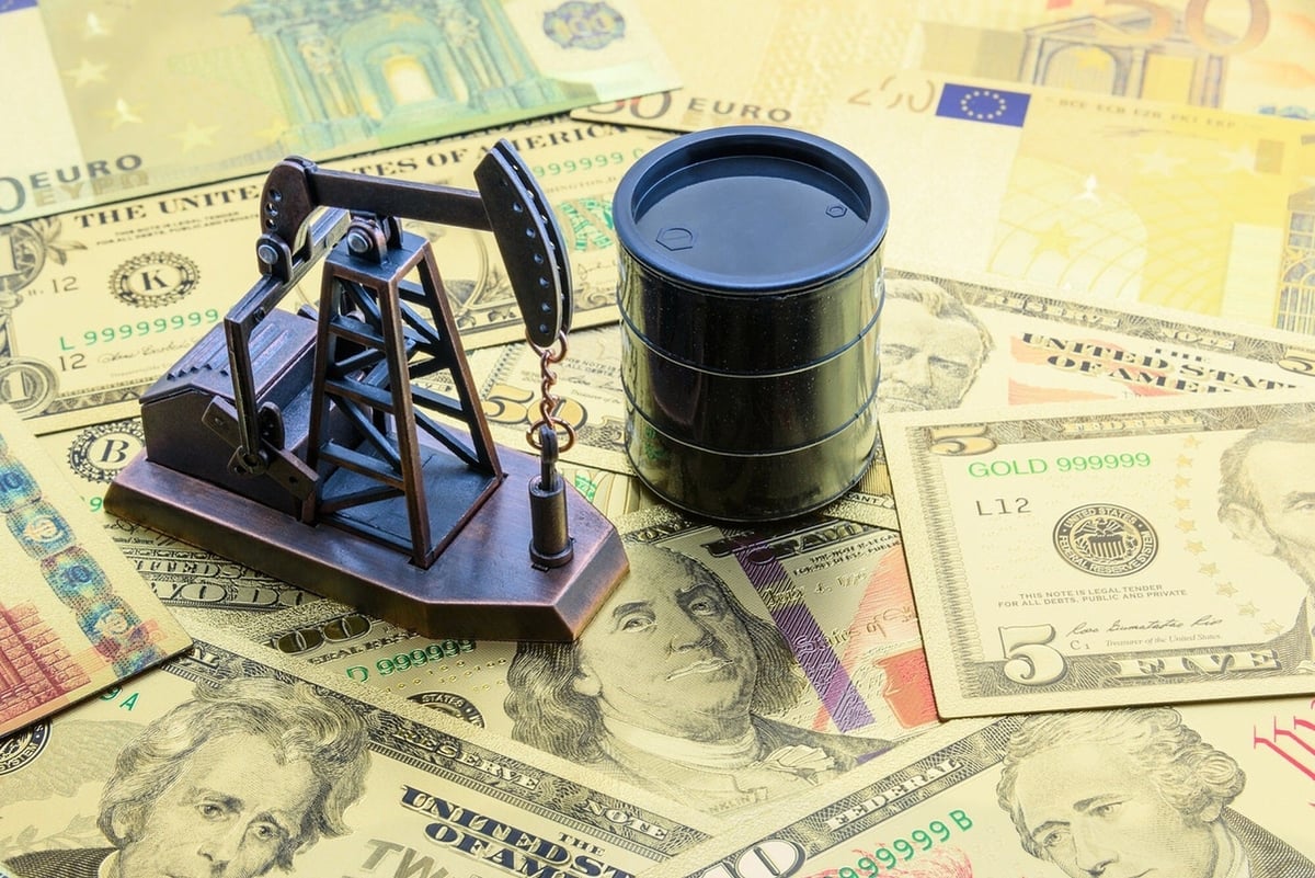An oil pump and a barrel sitting on a pile of money.