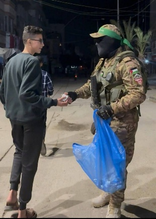 An operative of Hamas' military wing distributes pastries (Telegram channel Murasel Kataeb al-Qassam, March 21, 2026)