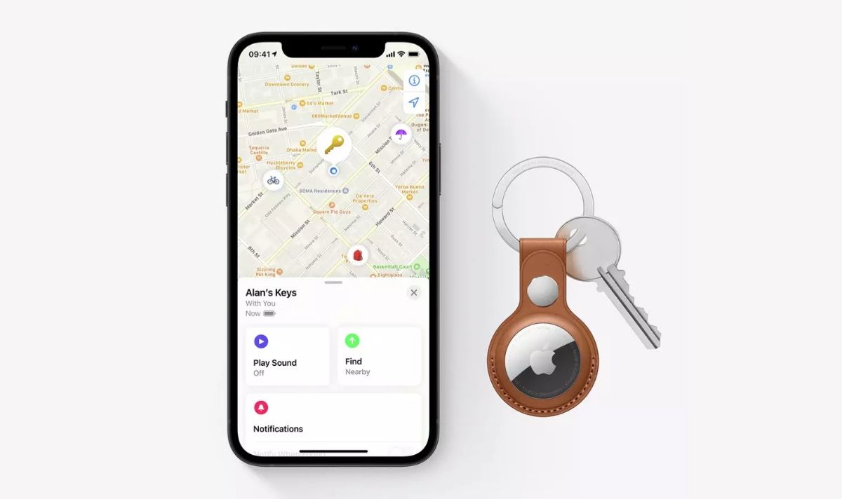 An iPhone displaying a map beside a key with an Apple AirTag attached via a keyring.