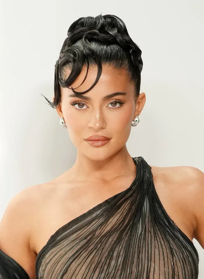 Kylie Jenner in elegant sheer dress with intricate updo hairstyle
