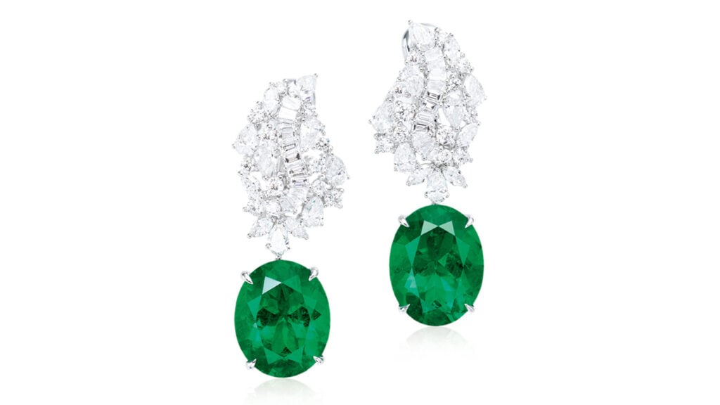 A pair of earrings with oval-cut Colombian emeralds — one 5.61 carats, the other 5.26 carats — hanging from clusters of pear, baguette and circular-cut diamonds at Poly Auction image