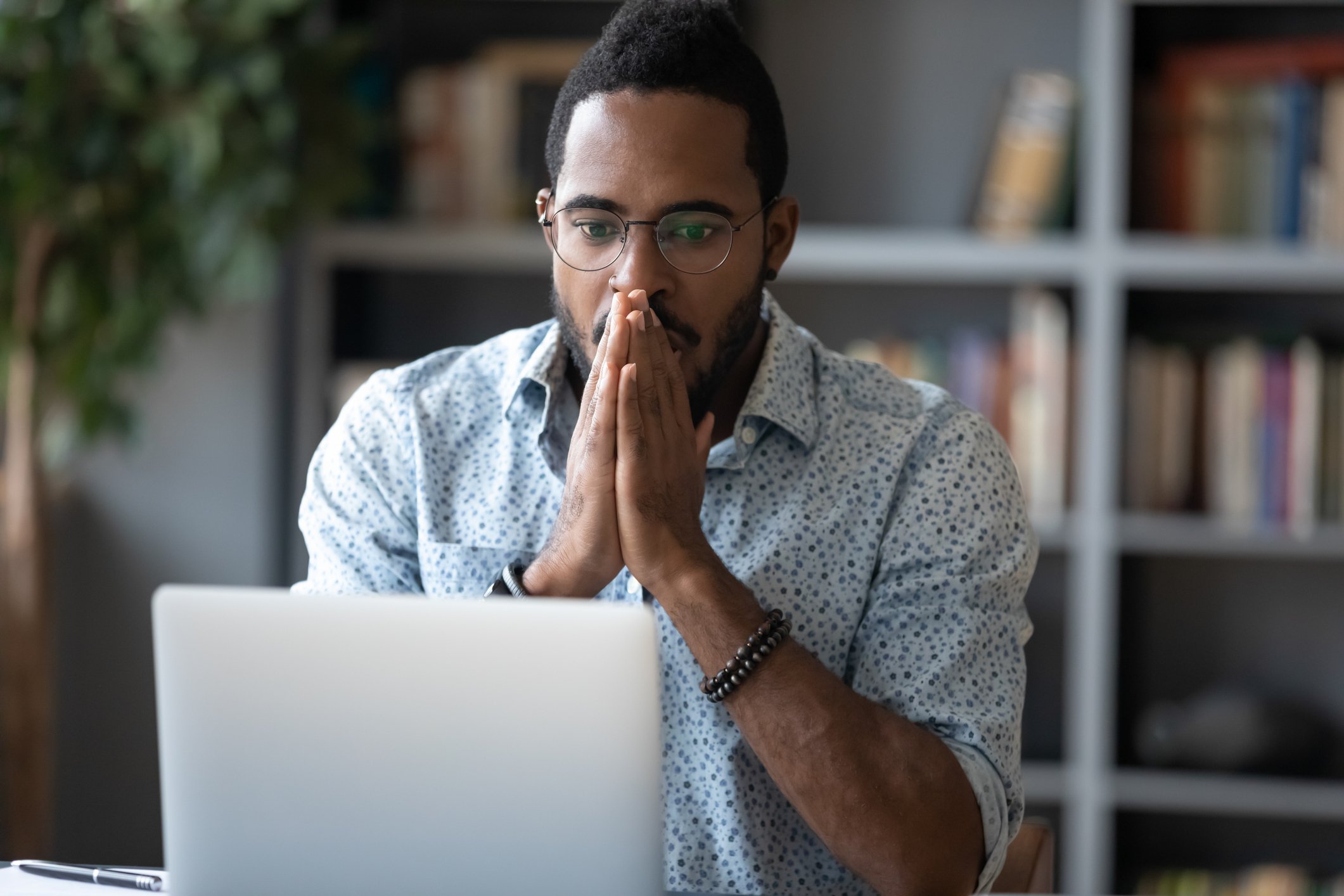 An investor looks surprised while studying something on a laptop.