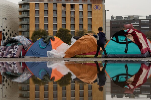 FILE — A child walks past tents sheltering people displaced by Israeli airstrikes in southern Lebanon and Dahiyeh, Beirut's southern suburbs, along the Beirut waterfront in Beirut, Lebanon, Saturday, March 14, 2026. (AP Photo/Hassan Ammar, File)