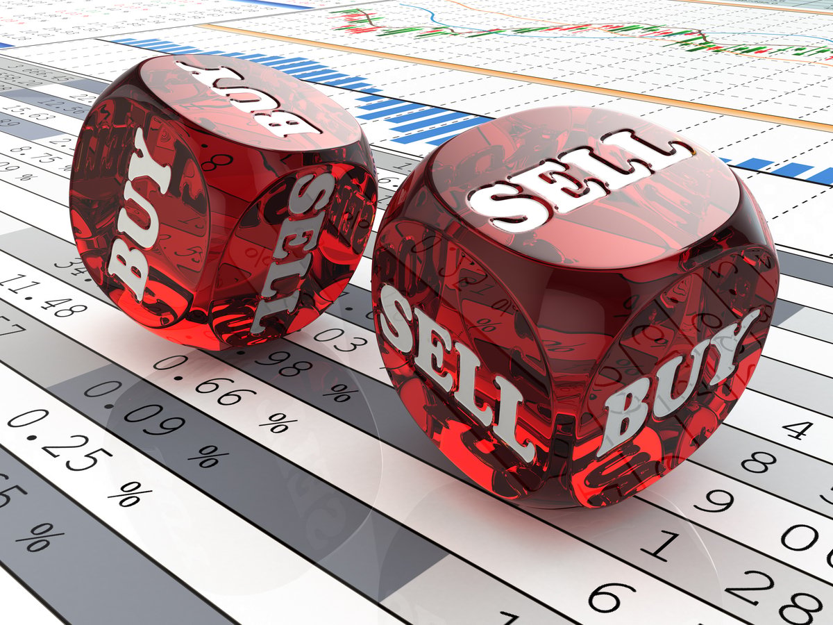 Dice reading Buy and Sell on their sides on top of a financial statement.