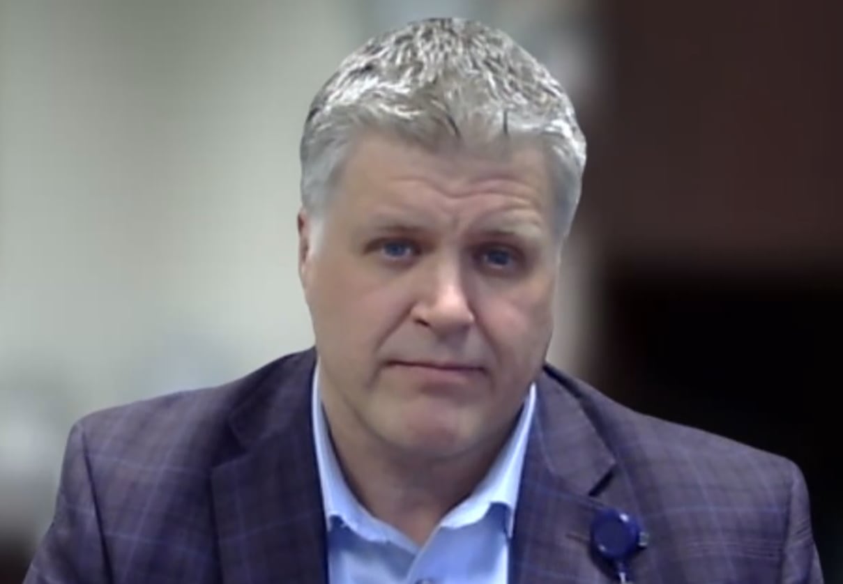 A gray-haired man in a suit in an office.