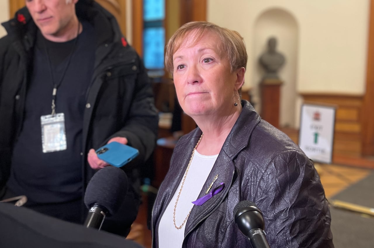 Woman with short blonde hair in a leather jacket.