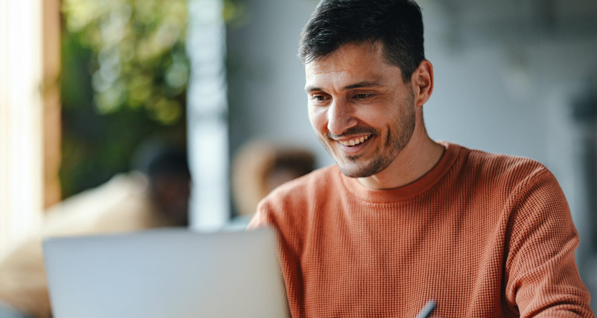 Male employee smiling while reading his laptop.