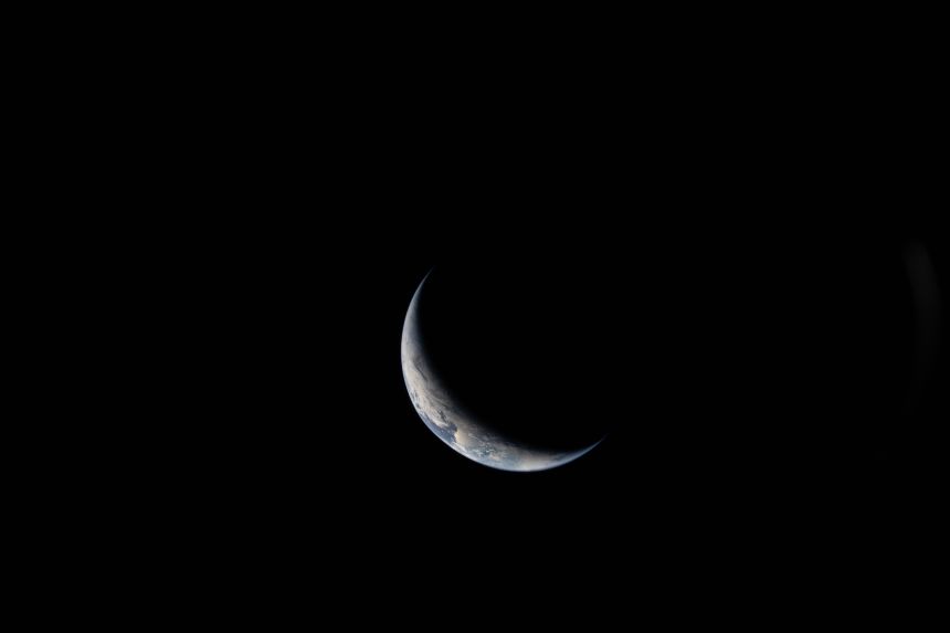 Earth is illuminated against the blackness of space in this photo taken by an Artemis II crewmember through one of Orion's windows on Day 3 of the mission.