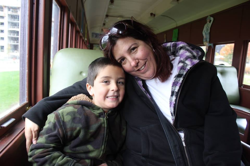 A mother and son snuggle on a train.