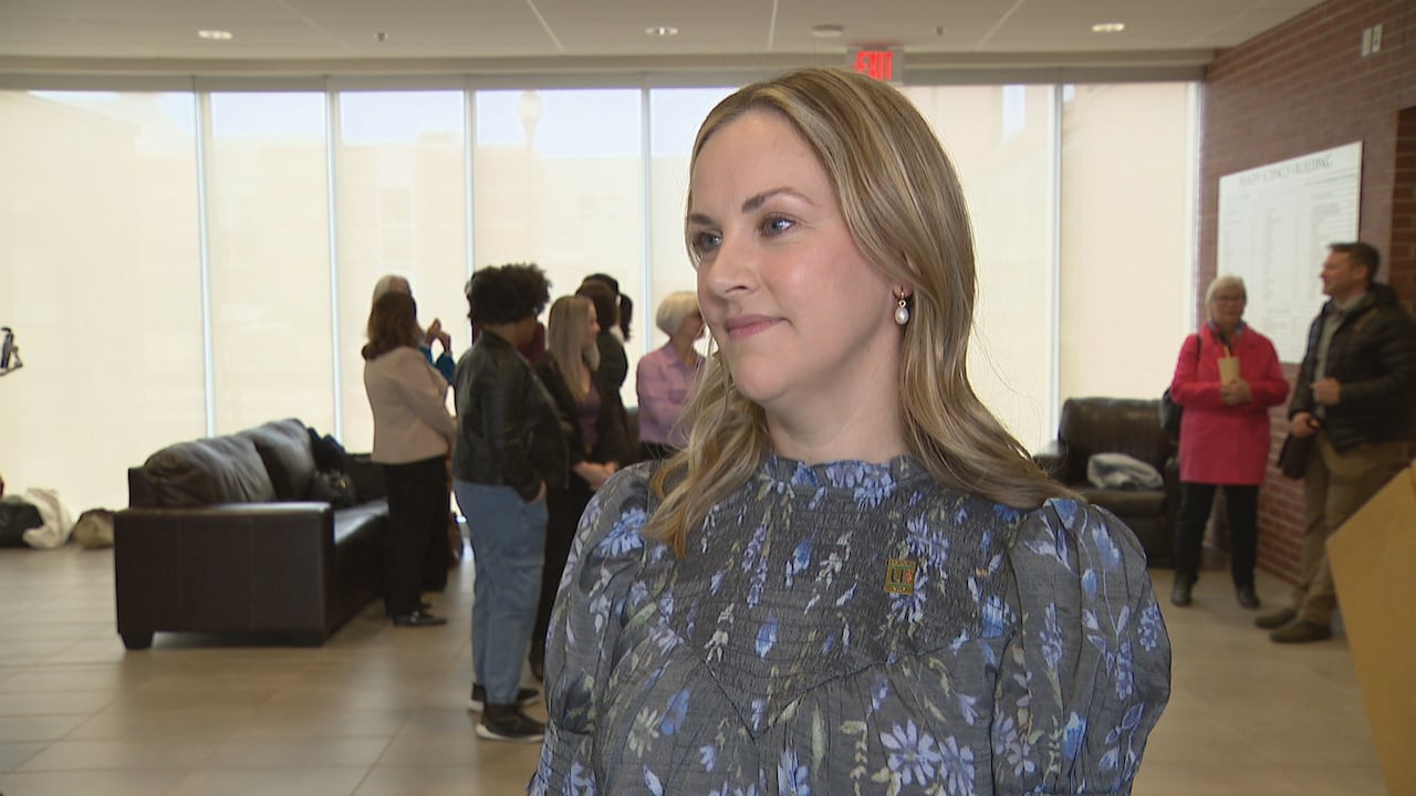 A woman in a floral shirt taking questions.