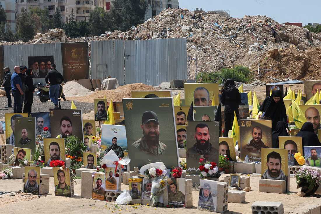 People stand amid the graves of Hezbollah fighters killed in Israeli strikes, at a cemetery in Choueifat on April 13, 2026.